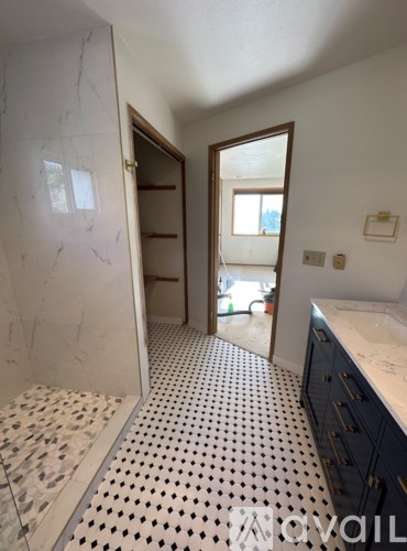 A bathroom with a marble shower and a tiled floor.
