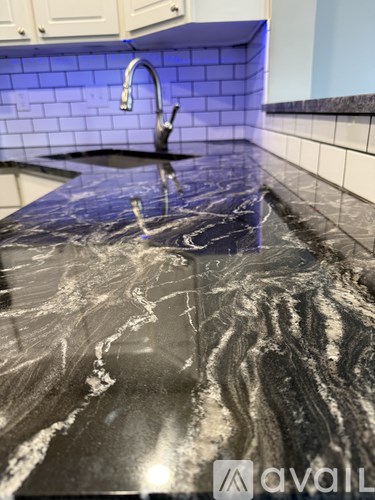 A kitchen counter with a marble top and a black sink.