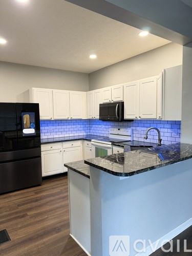 A kitchen with white cabinets and a black fridge.