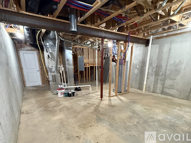 A room under construction with exposed pipes and wooden beams.
