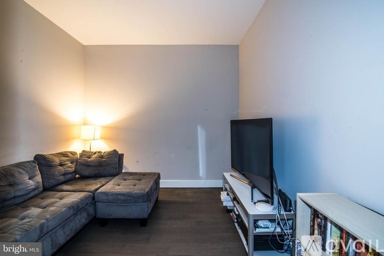 A living room with a grey sofa, a television, and a floor lamp.