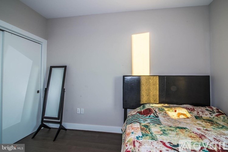 A bedroom with a bed, a mirror, and a dresser.
