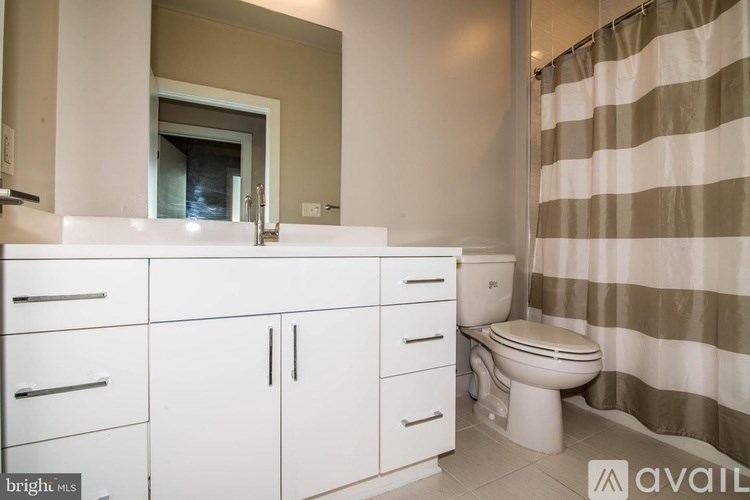 A bathroom with a toilet, sink, and cabinets.