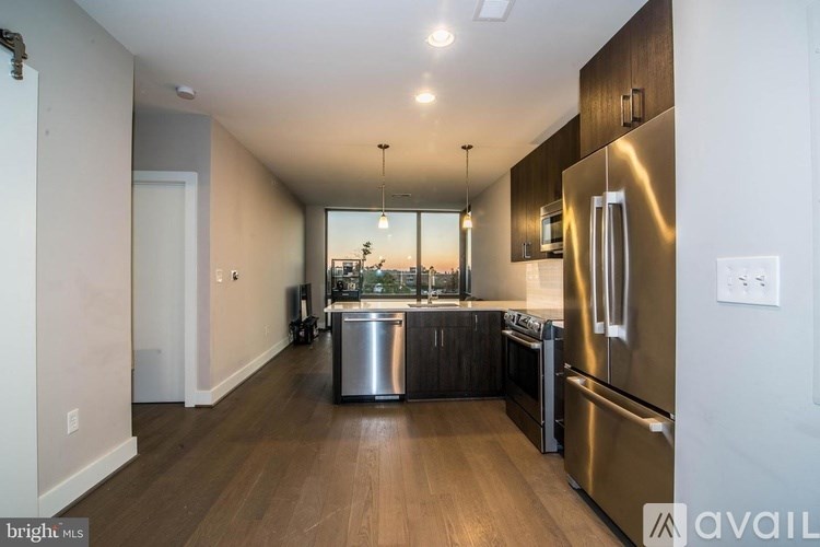 A modern kitchen with stainless steel appliances and wooden floors.