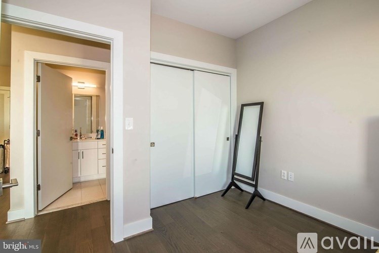 A room with a white door and a white framed mirror on a stand.
