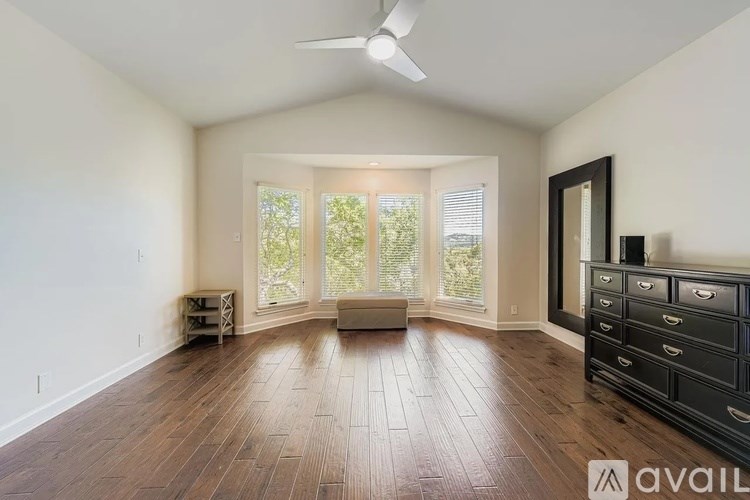 A spacious room with wood flooring and a ceiling fan.