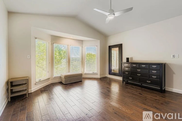 A room with a ceiling fan and a dresser with a mirror above it.