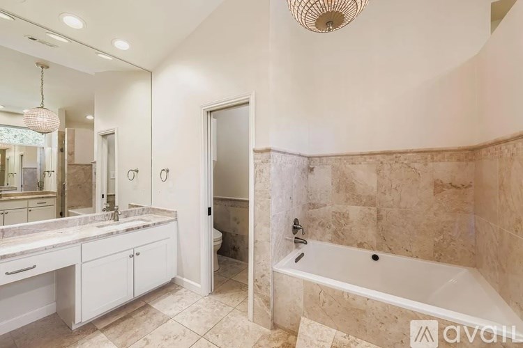 A bathroom with a tub, sink, and mirror.