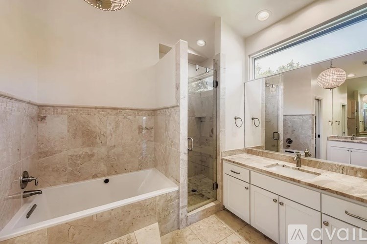A bathroom with a tub, sink, and mirror.