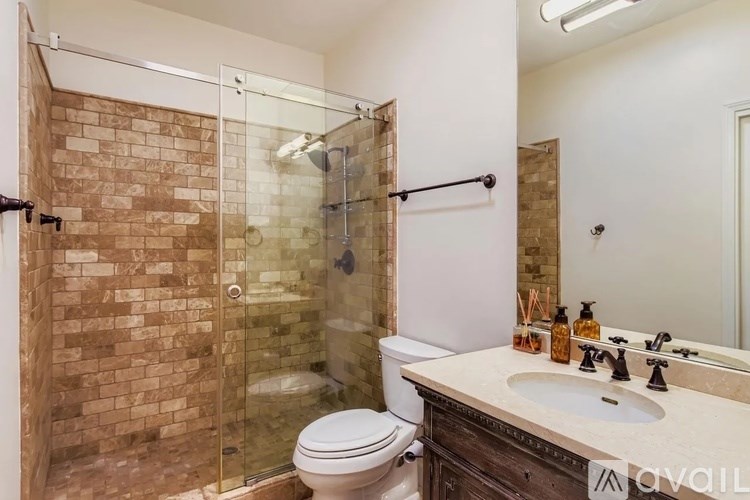A bathroom with a toilet, sink, and shower with a glass door.