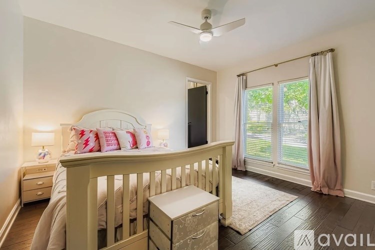 A bedroom with a bed, dresser, and window with curtains.