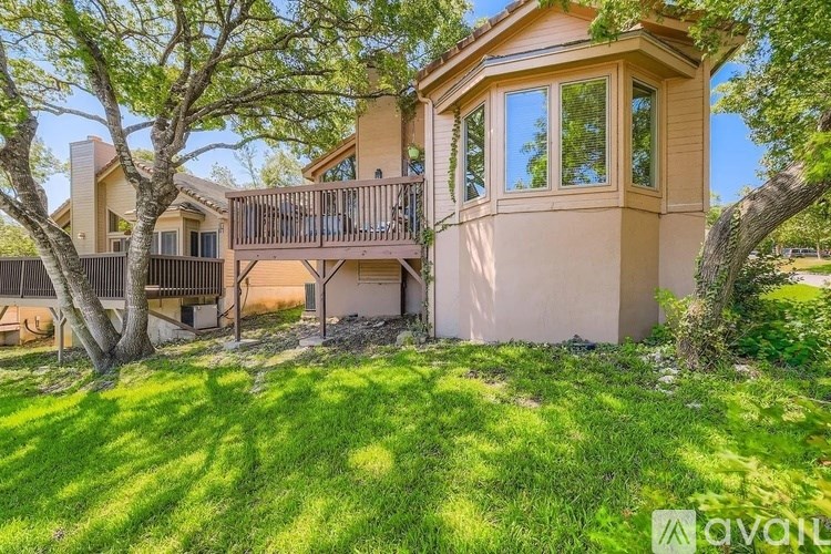 A house with a balcony and a tree in front of it.