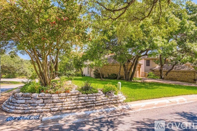 A stone wall with a "No Parking" sign in front of a house.