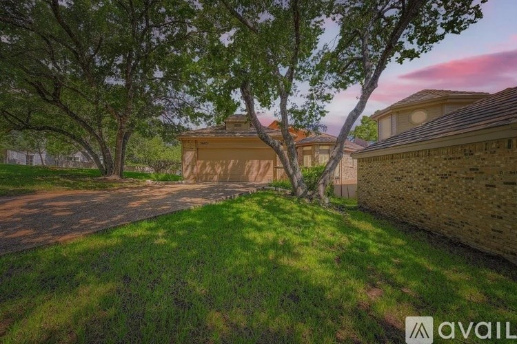 A house with a brown roof is surrounded by trees and grass.