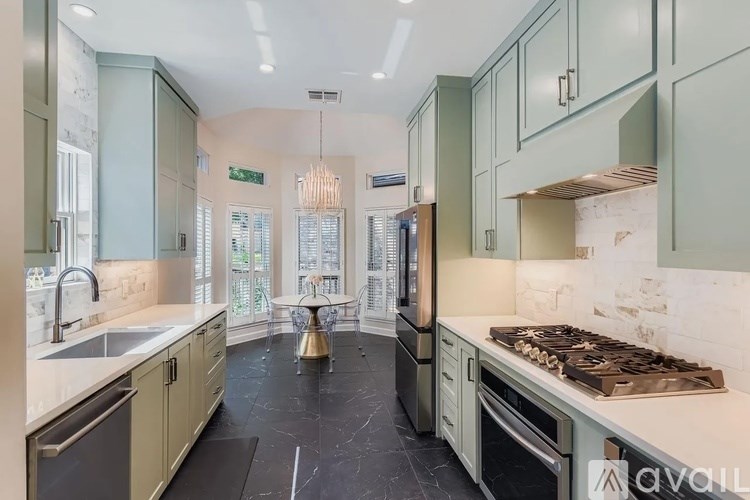 A kitchen with green cabinets and a black floor.