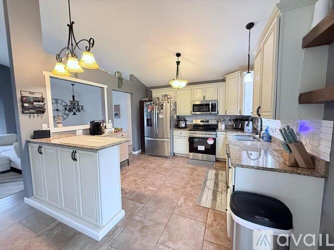 A kitchen with a white cabinet and a black trash can.