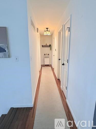 A long hallway with white walls and a wooden floor.