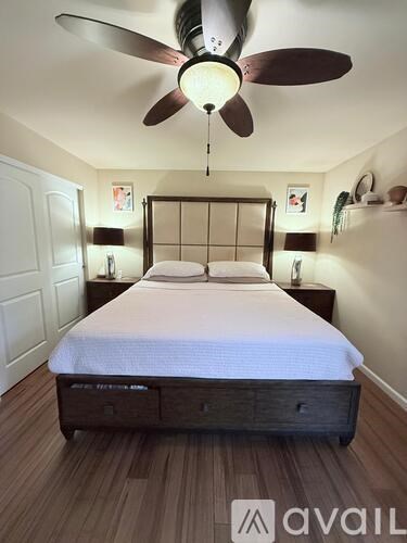 A bedroom with a bed, nightstand, and a ceiling fan.