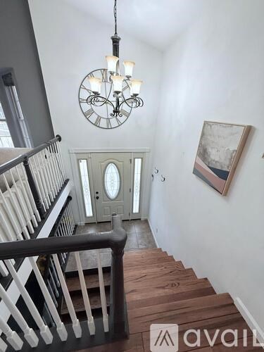 A staircase with a wooden handrail and a chandelier hanging from the ceiling.