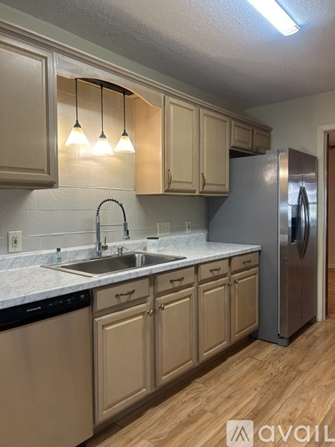 A kitchen with wooden cabinets and a stainless steel refrigerator.