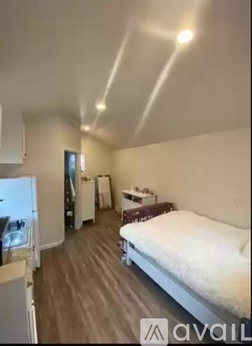 A bedroom with a bed, a refrigerator, and a washing machine.