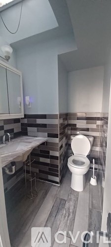 A bathroom with a toilet, sink, and mirror.