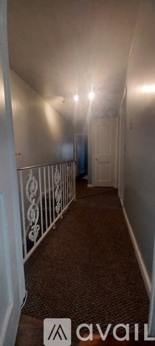 A hallway with a carpeted floor and white walls.