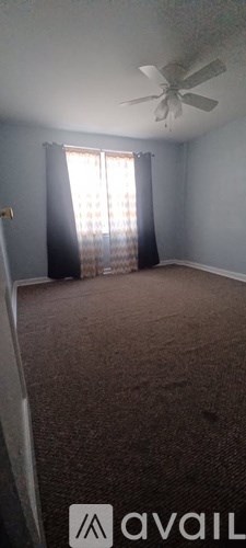 A room with a carpeted floor and a ceiling fan.