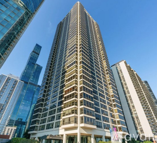 A tall building with a lot of windows stands in front of other buildings.