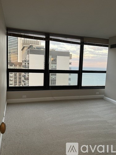 A carpeted room with a large window overlooking a cityscape.
