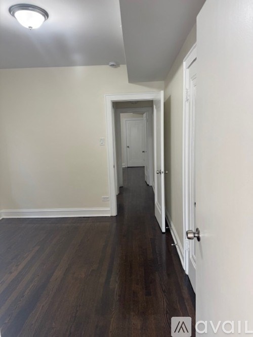 A long hallway with wood floors and white walls.