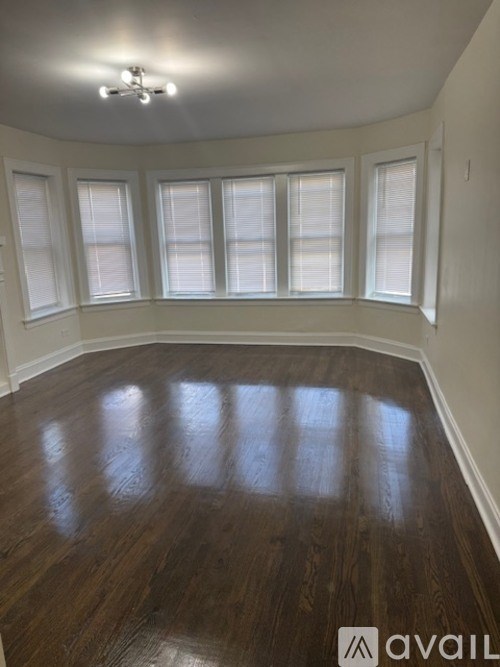 A room with wooden floors and a window with blinds.