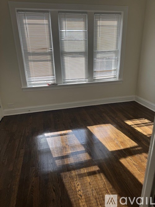 A room with wooden floors and a window with blinds.