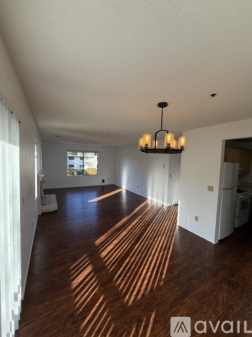 A room with wooden floors and a chandelier hanging from the ceiling.