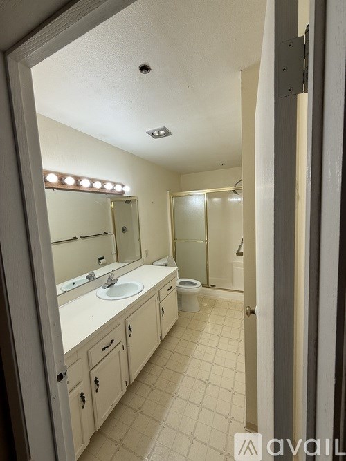 A bathroom with a sink, mirror, toilet and shower.