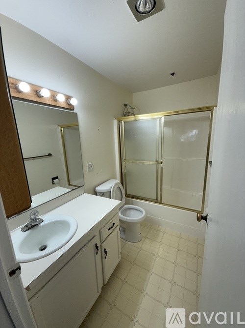A bathroom with a sink, toilet, and mirror.