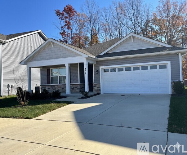 A black leather sofa with a yellow pillow sits in a living room.