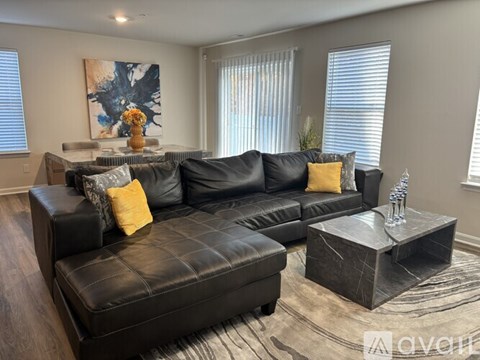 A black leather sofa with a yellow pillow sits in a living room.