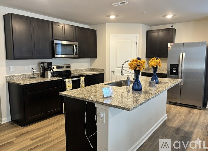 A living room with a black leather couch and a television mounted on the wall.