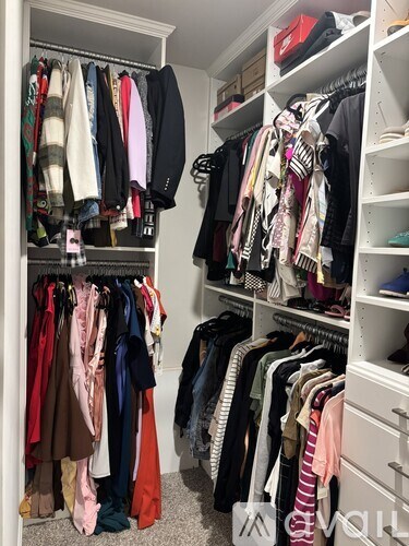 A white closet with clothes hanging on shelves and hangers.