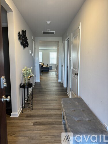 A hallway with a bench and a flower vase on a table.