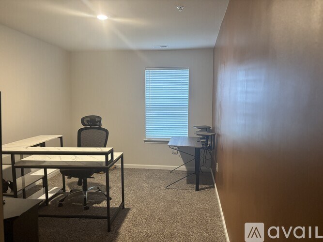 A room with a desk, chair, and a window with blinds.