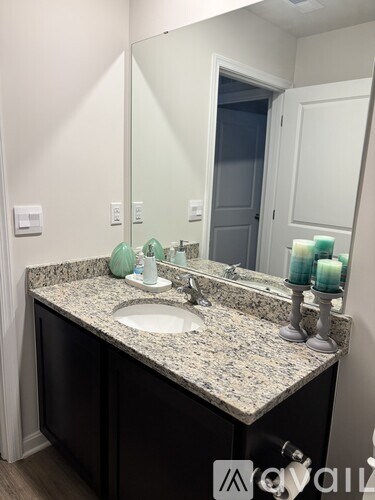 A bathroom vanity with a granite countertop and a large mirror above the sink.