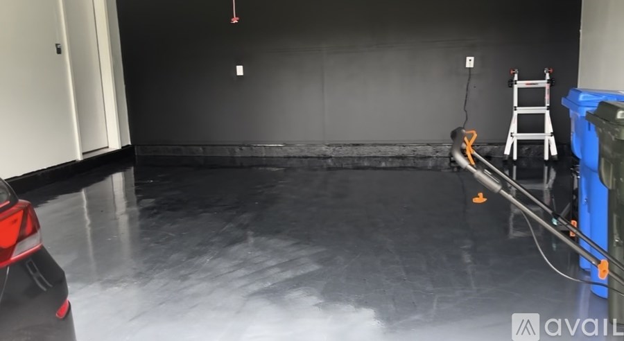 A room with a black floor and a red car in the foreground.