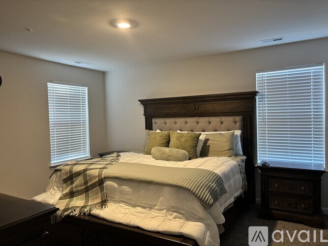 A bedroom with a bed, nightstand, and window with blinds.