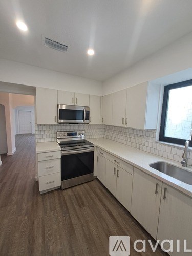 A kitchen with white cabinets and a wooden floor.