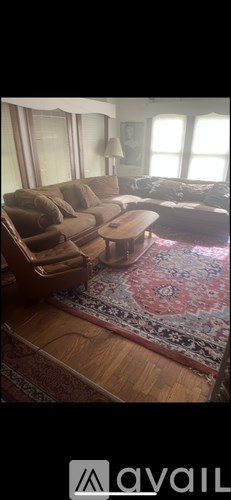 A living room with a brown couch and a rug.