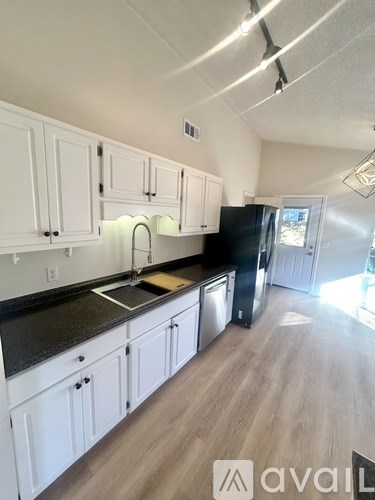 A kitchen with white cabinets and black countertops.