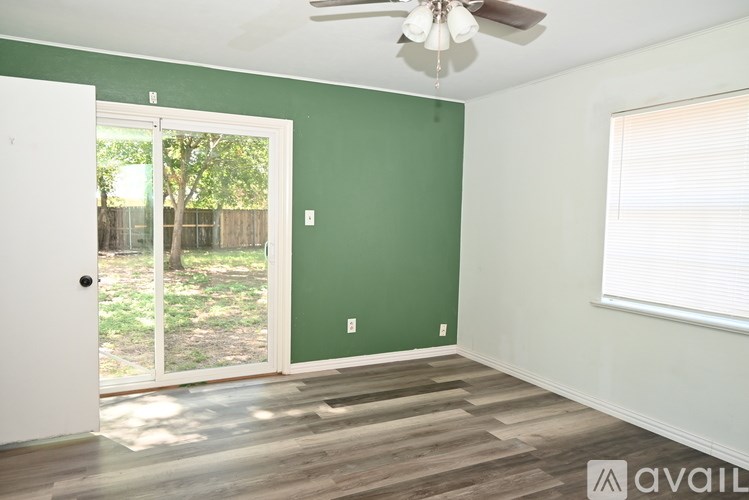 A room with a ceiling fan and a sliding glass door leading to a backyard.