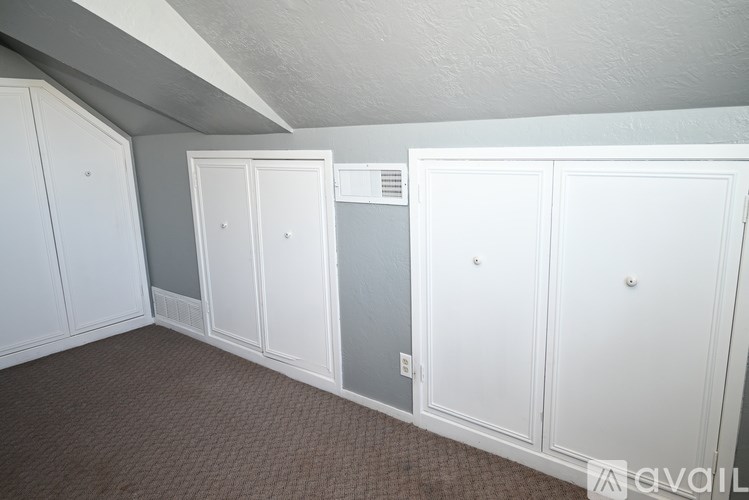 A room with white cupboards and a grey wall.